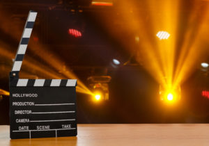 Illuminated Movie Camera With Clapperboard And Film Reel Against